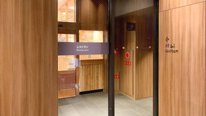 A wooden interior with a glass door leading to a restroom, marked with accessibility symbols. - Comfort Inn Fukuoka Tenjin (Fukuoka)