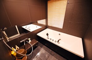 Un baño moderno con una bañera grande, dos lavamanos y un espacio de tocador.