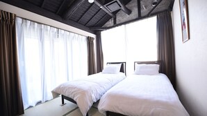 A hotel room with two beds, large windows with curtains, a wooden ceiling, and a framed picture on the wall. - Kyobijin (Kyoto)
