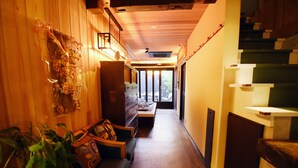 A narrow hallway with wooden walls, a bench, and a staircase. - Kyobijin (Kyoto)
