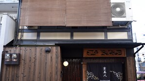 A traditional Japanese building with a wooden facade, a sliding shoji door, and a sign reading "Guesthouse Iwaki". - Kyobijin (Kyoto)