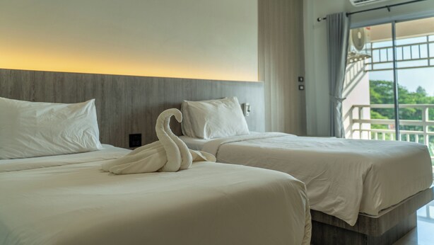 A hotel room with two beds, a large window with a view, and an air conditioning unit. - Nonsi Hotel Phitsanulok (Phitsanulok)