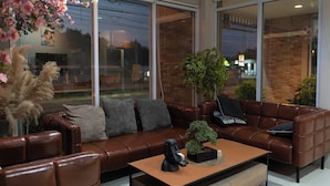 A modern living room with a brown leather sofa, a wooden coffee table, and a small potted plant. - Nonsi Hotel Phitsanulok (Phitsanulok)