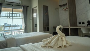 A hotel room with two beds, a desk, and a large window with a view of buildings. - Nonsi Hotel Phitsanulok (Phitsanulok)