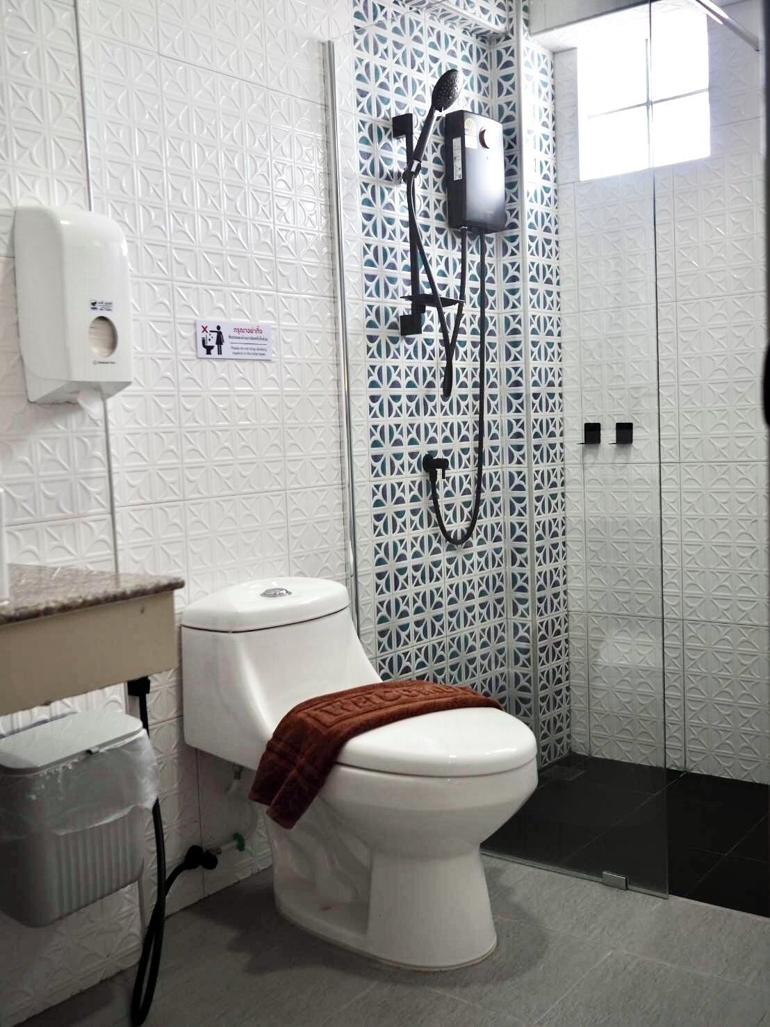 Un baño con inodoro, ducha y secador de manos.