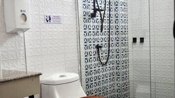 Un baño con inodoro, ducha y secador de manos.