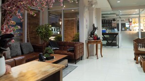 A modern hotel lobby with a leather sofa, a wooden coffee table, and a small statue. - Nonsi Hotel Phitsanulok (Phitsanulok)