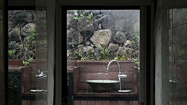 Un baño con tocador de madera, lavamanos y espejo.
