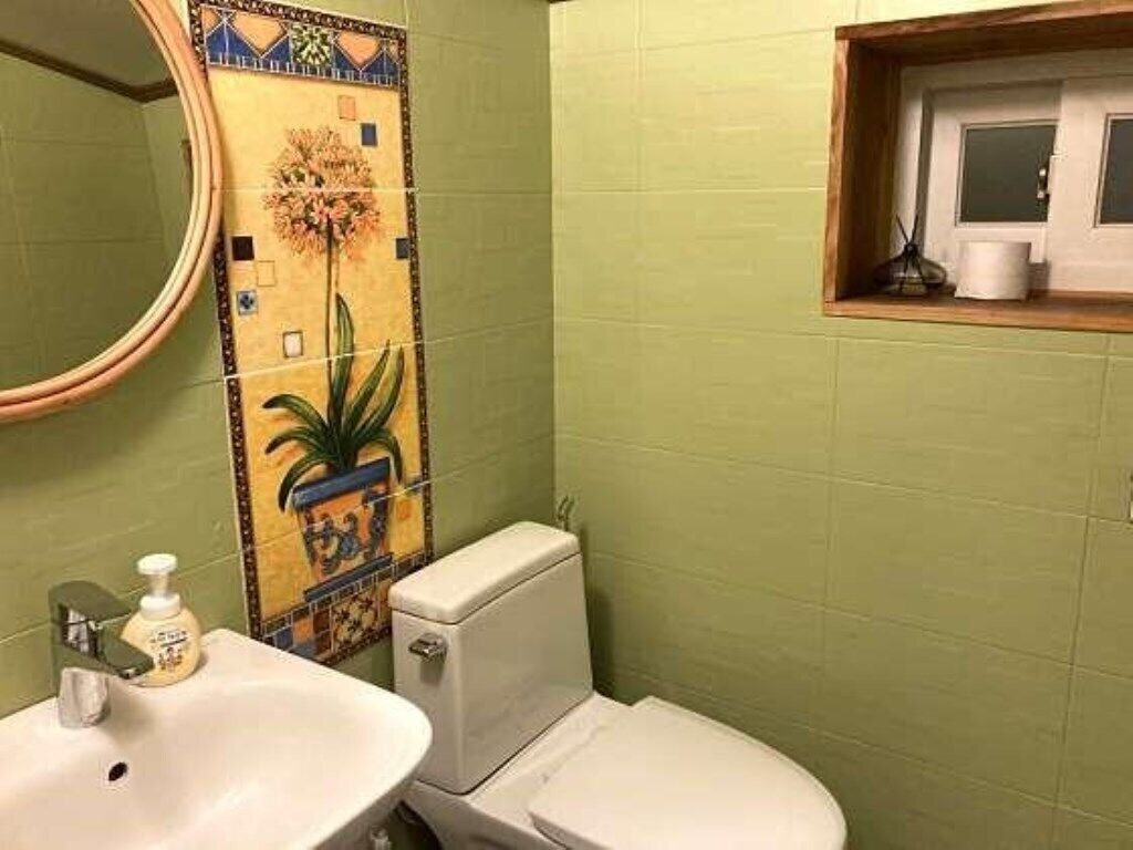 A bathroom with a toilet, sink, and a decorative tile backsplash.