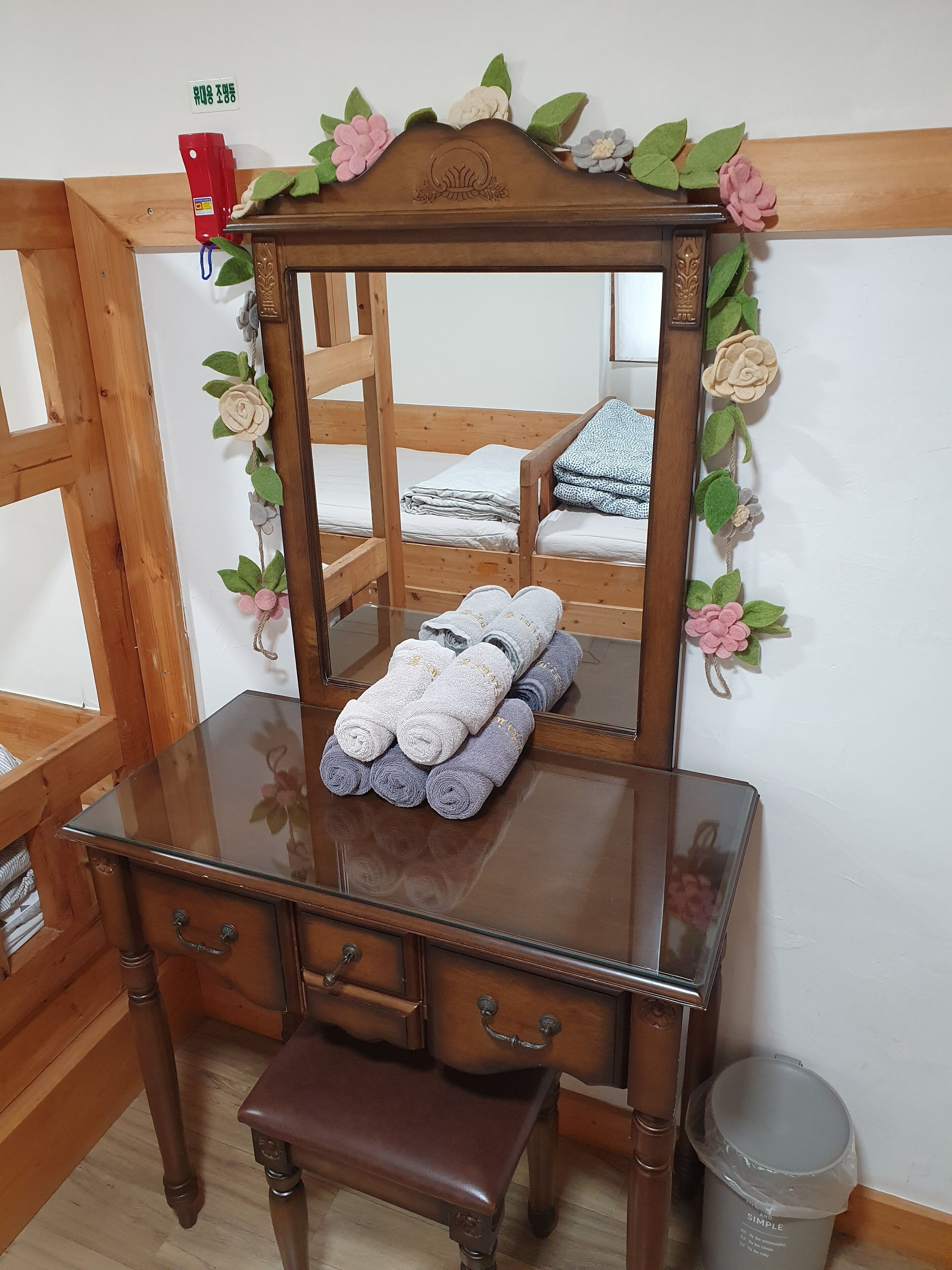 A wooden dresser with a mirror, a bench, and a bed with a wooden headboard.