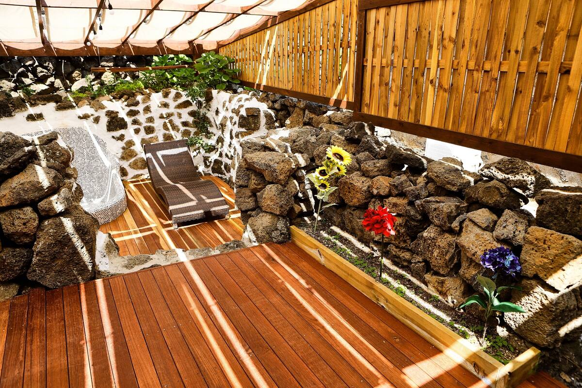 Een houten terras met een stenen muur en een houten hek.