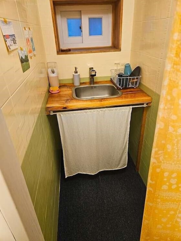 A compact kitchen with a wooden countertop, a stainless steel sink, and a small window above the sink.