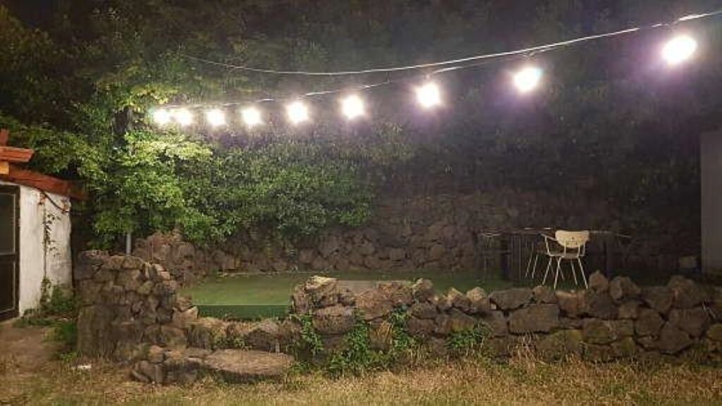Een buitengebied met een stenen muur, een tafeltje en lichtjes.