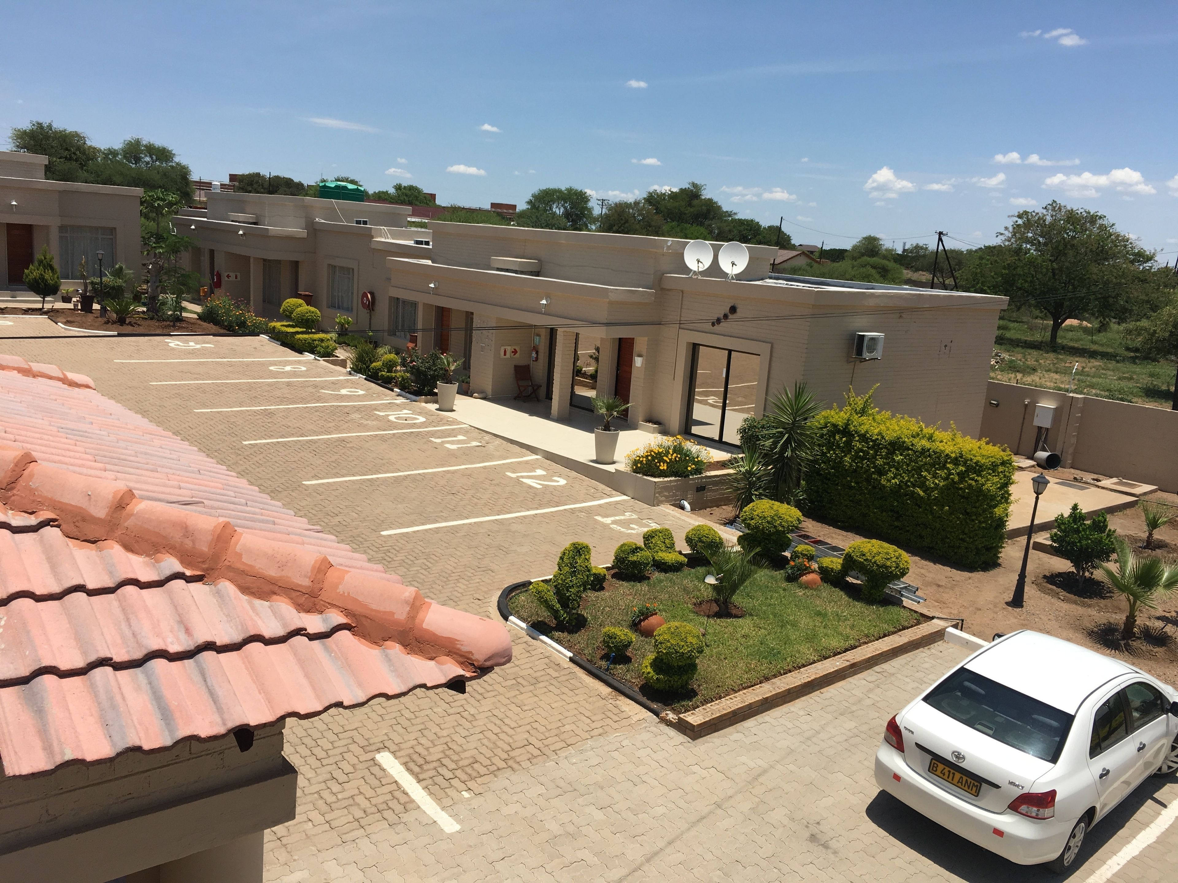 A parking lot with numbered spaces, a white car, and a building with satellite dishes.