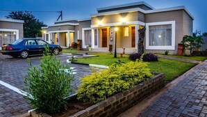 A modern hotel with a two-story structure, a paved driveway, and a well-maintained garden area.