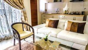 A modern living room with a white sofa, a wooden chair, and a glass coffee table.