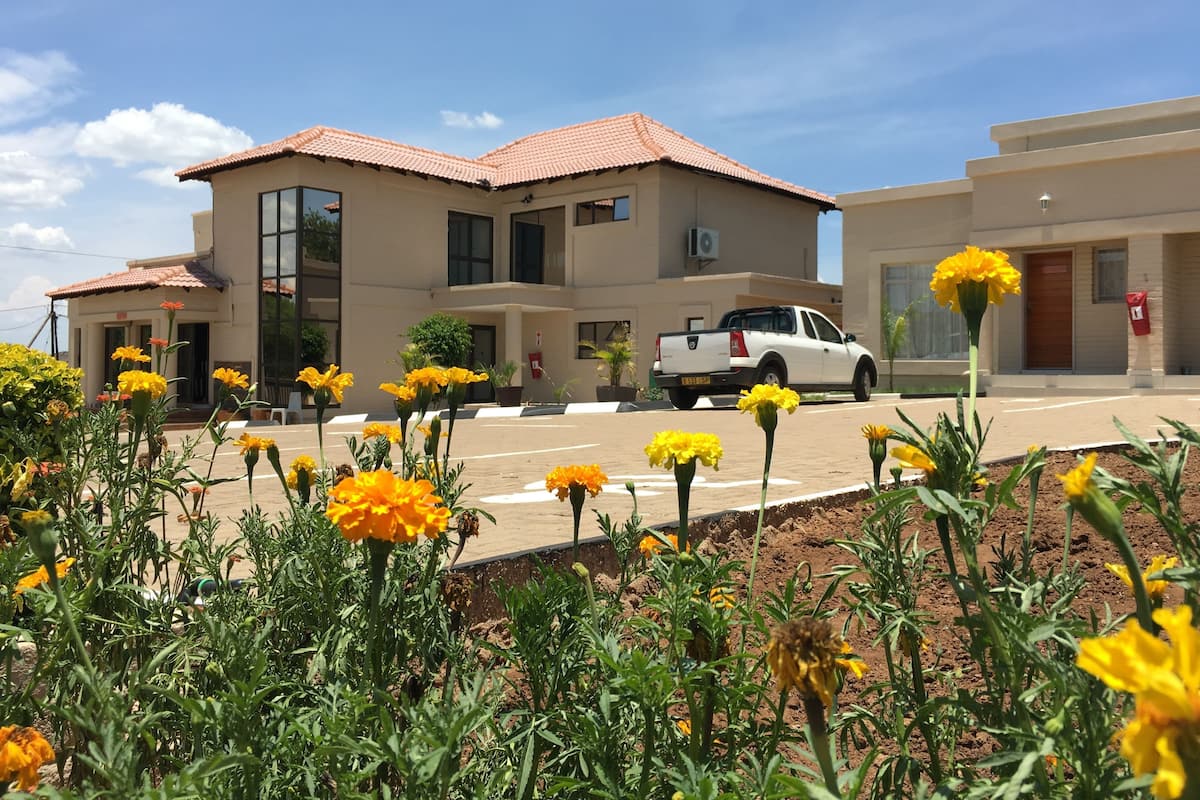Un bâtiment avec un toit recouvert de tuiles, un camionnette blanche garée devant, et des fleurs jaunes au premier plan.