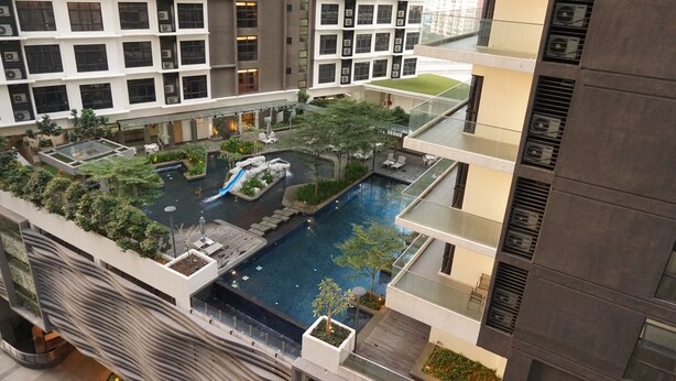 Un immeuble de grande hauteur doté de nombreux balcons, d’un jardin sur le toit et d’une piscine centrale.