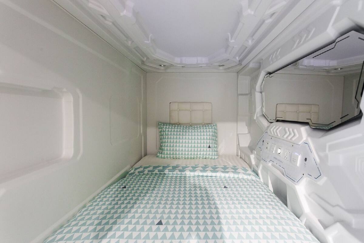 A small, compact room with a single bed, a headboard, and a bedside table.