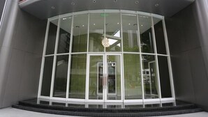 A modern building entrance with a glass facade and a curved roof. - Vortex Suite KLCC at Penguin Homes (Kuala Lumpur)