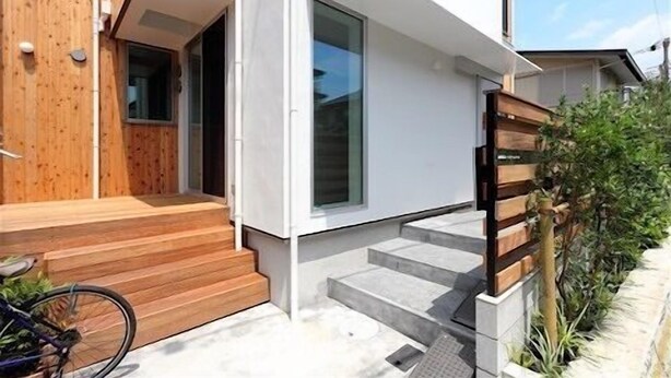 A modern house with a wooden exterior, a front porch, and a staircase leading to the entrance. - Shonan-Enoshima Seaside Guest House – Hostel (Fujisawa)