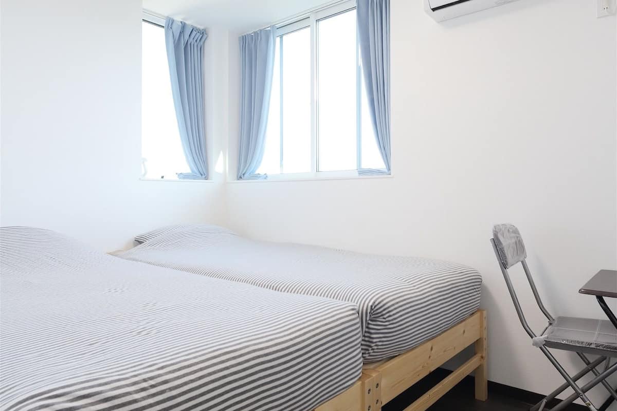Une chambre avec deux lits, un bureau et un appareil de climatisation.