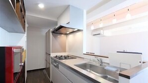 A modern kitchen with a gas stove, stainless steel sink, and built-in oven. - Shonan-Enoshima Seaside Guest House – Hostel (Fujisawa)