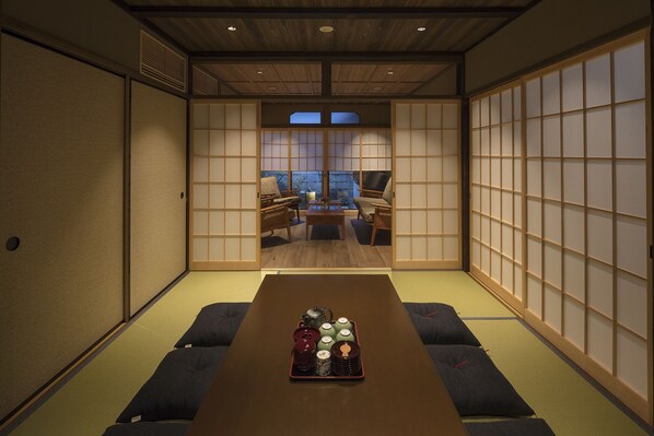 Una habitación japonesa tradicional con suelo de tatami, una mesa baja con servicios de té y puertas correderas.