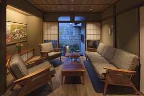 Um quarto tradicional japonês com piso de tatame, uma mesa de madeira baixa e um sofá.