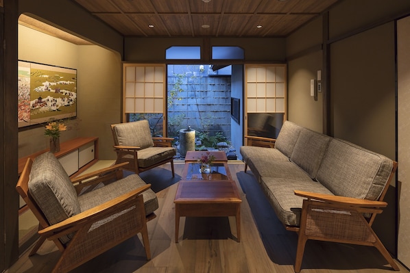 Traditional Japanese living room with tatami mat floor, sofa, armchairs, and sliding shoji screen door.