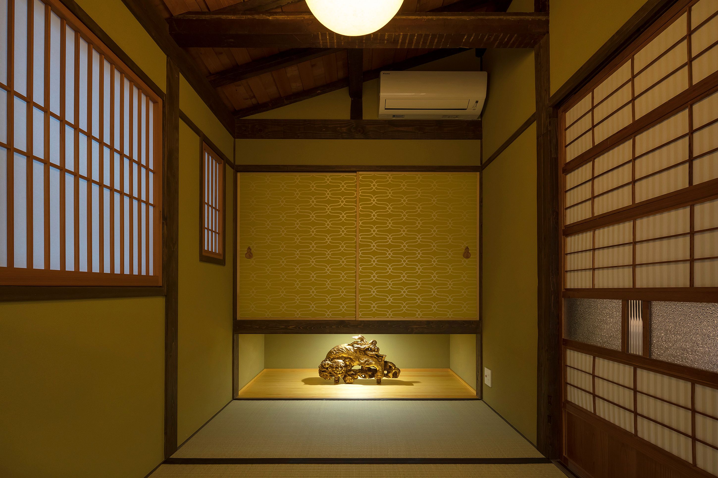 A traditional Japanese room with tatami flooring, shoji screens, and a ceiling fan.
