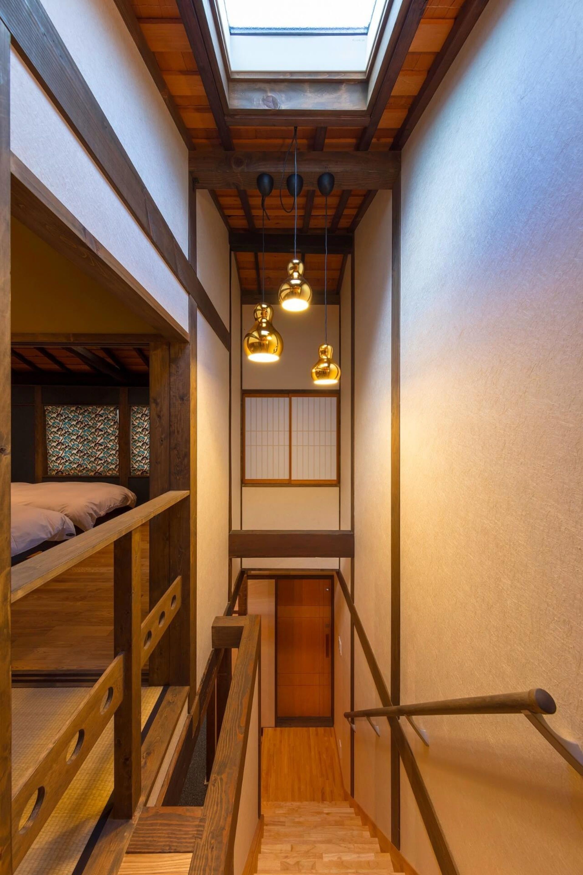 Un escalier étroit avec des rampes en bois et une lucarne au-dessus.