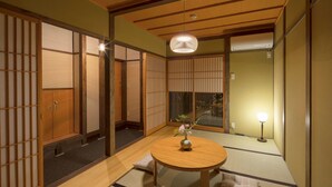 Et traditionelt japansk rum med tatamimåtter, et rundt træbord og shoji-skærme.