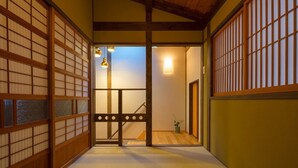 Et traditionelt japansk interiør med tatamimåtter, skydedøre og en trappe til et andet rum.