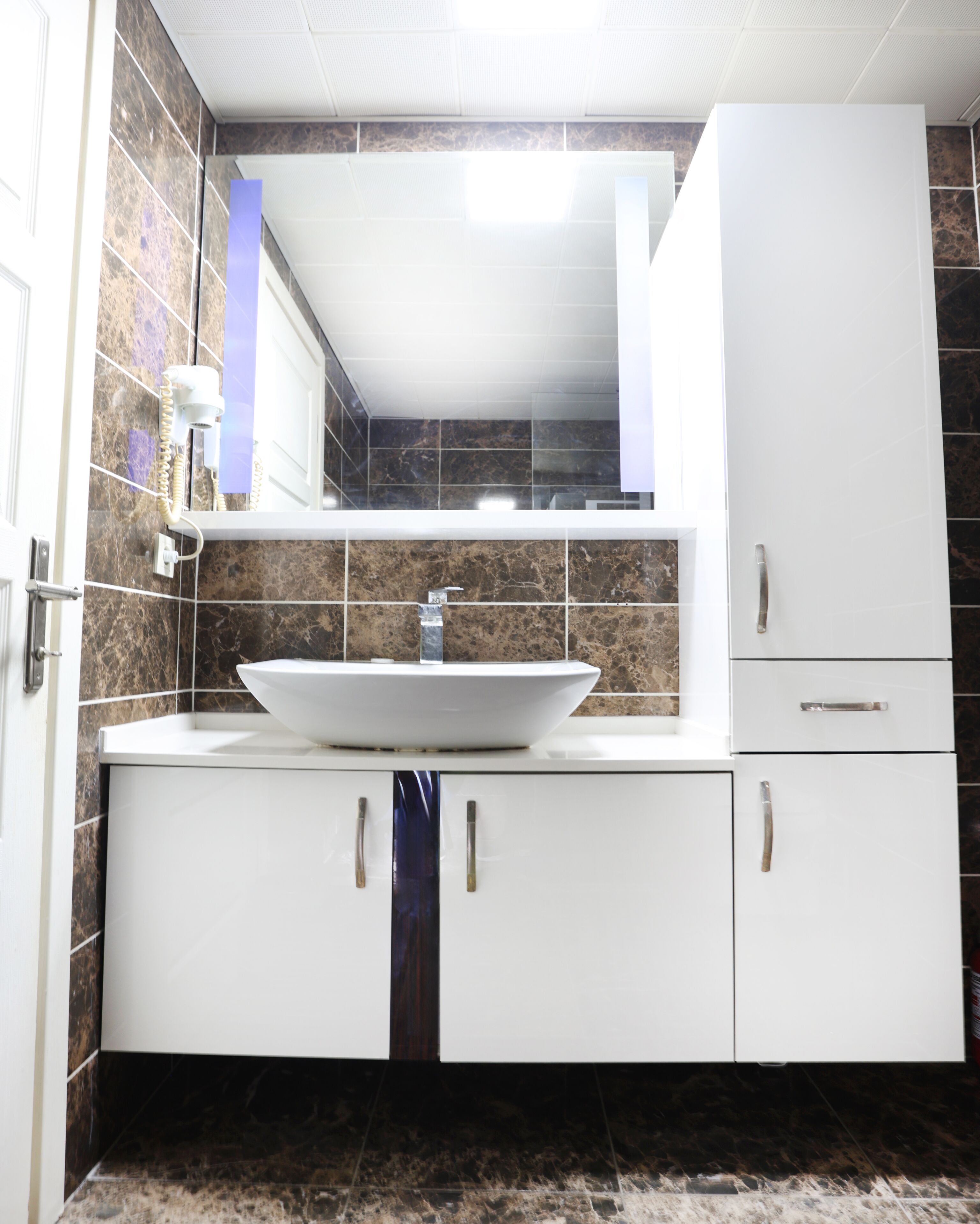 A bathroom with a white sink, a mirror above it, and cabinets below.