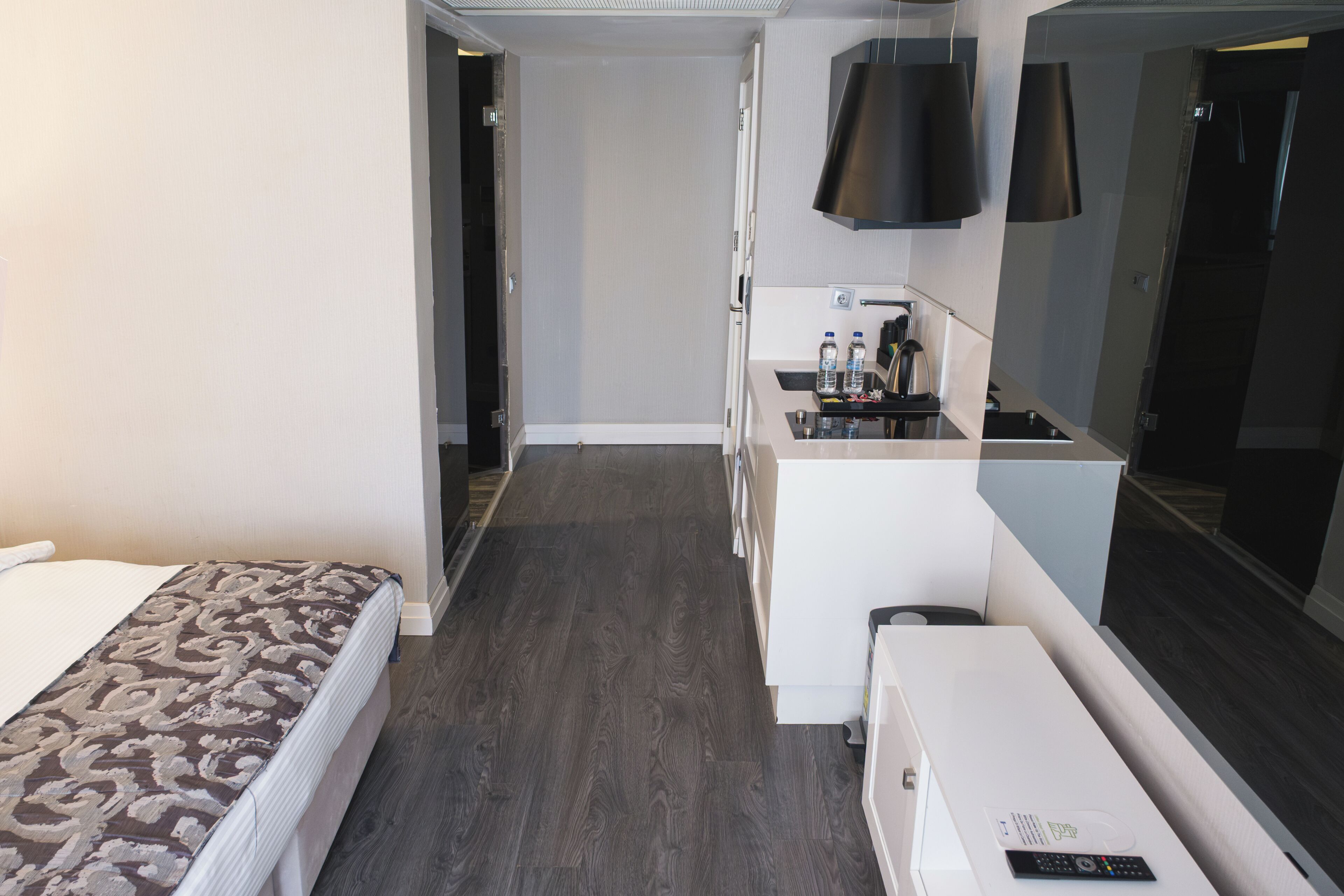 A hotel room with a bed, a small kitchenette, a mirror, and a walk-in closet.