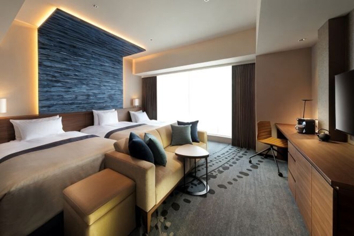 Habitación de hotel con una cama grande, un sofá, un escritorio y un televisor.