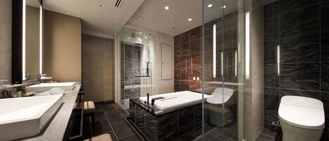 A modern bathroom with a glass-enclosed shower, a freestanding bathtub, and a toilet.