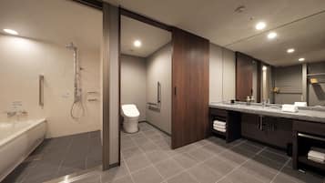 A modern bathroom with a bathtub, shower, toilet, and vanity with a mirror.