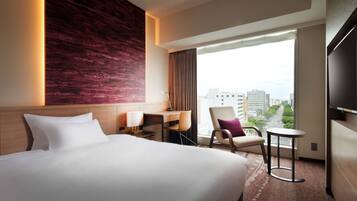 A hotel room with a large bed, a desk, a chair, a small table, and a TV.