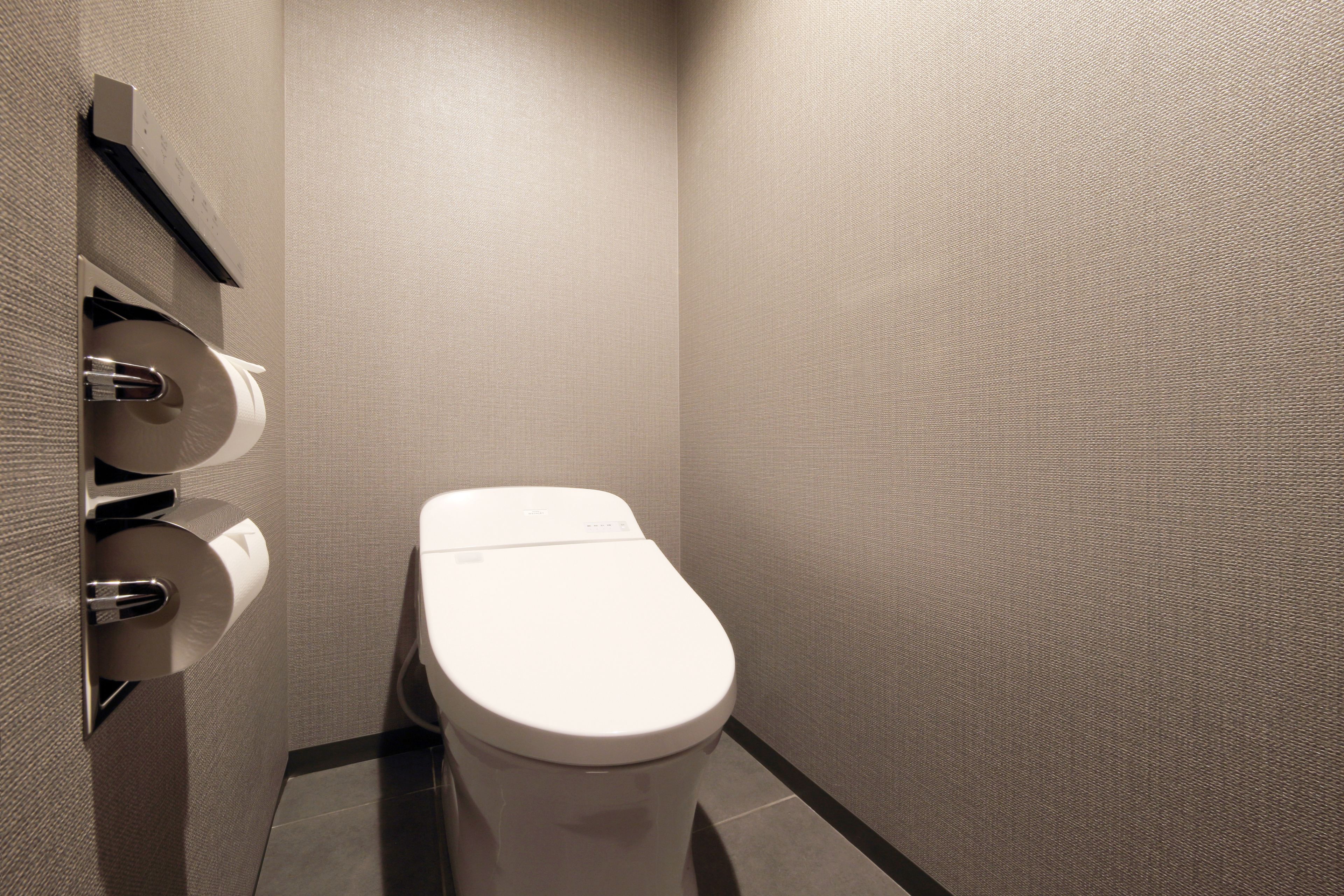 A modern bathroom with a toilet, a paper towel dispenser, and a hand dryer.
