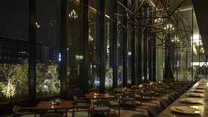 A restaurant with a long dining area, multiple tables, and chairs.