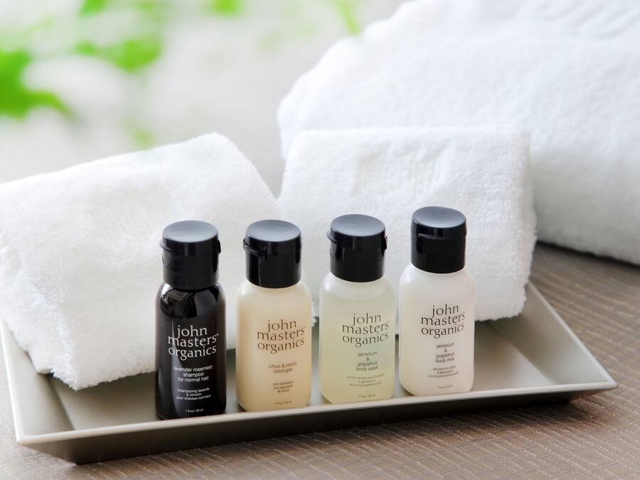 A tray with four bottles of John Masters Organics body wash and a white towel.