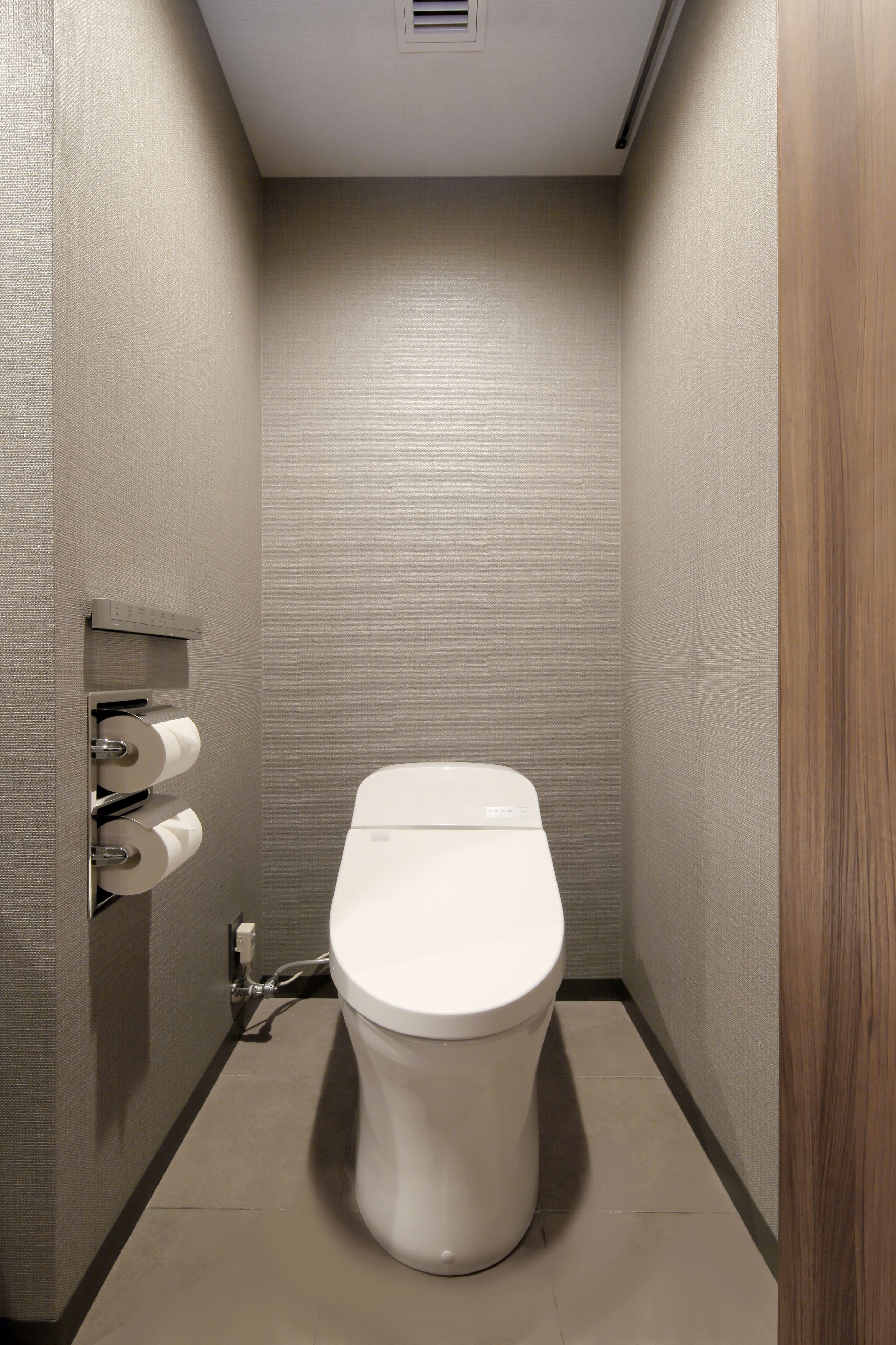 A small, modern bathroom with a toilet, a paper towel dispenser, and a hand dryer.