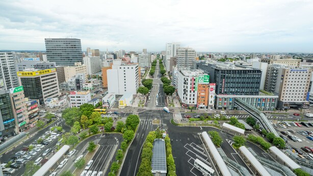 Un paisaje urbano con edificios modernos, una intersección central y una estación de autobuses.