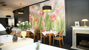 A dining area with tables set for service, a fireplace, and a large floral mural on the wall. - Hotel Pflug Ottenhöfen (Ottenhofen im Schwarzwald)