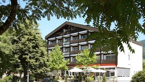A multi-story hotel with balconies, outdoor seating, and a parking area. - Hotel Pflug Ottenhöfen (Ottenhofen im Schwarzwald)