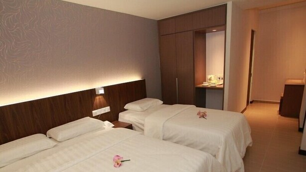 A hotel room with two beds, a nightstand, a mirror, and a small table with a lamp. - Tai Ichi Hotel (Kuala Lumpur)