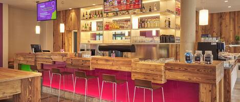 A bar area with wooden furniture, a TV screen, and shelves of bottles.