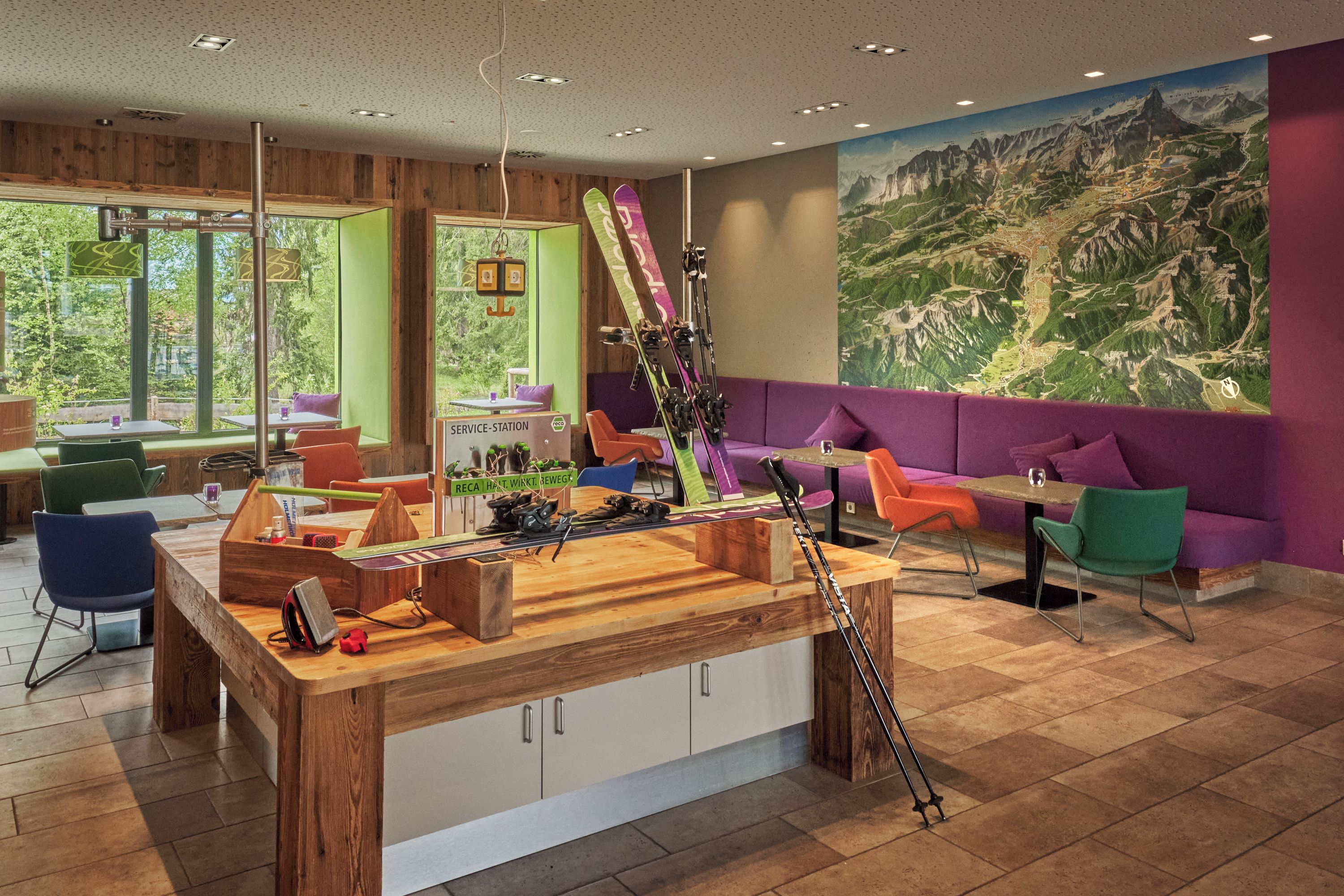 A modern interior with a wooden reception desk, seating area, and a large map mural.